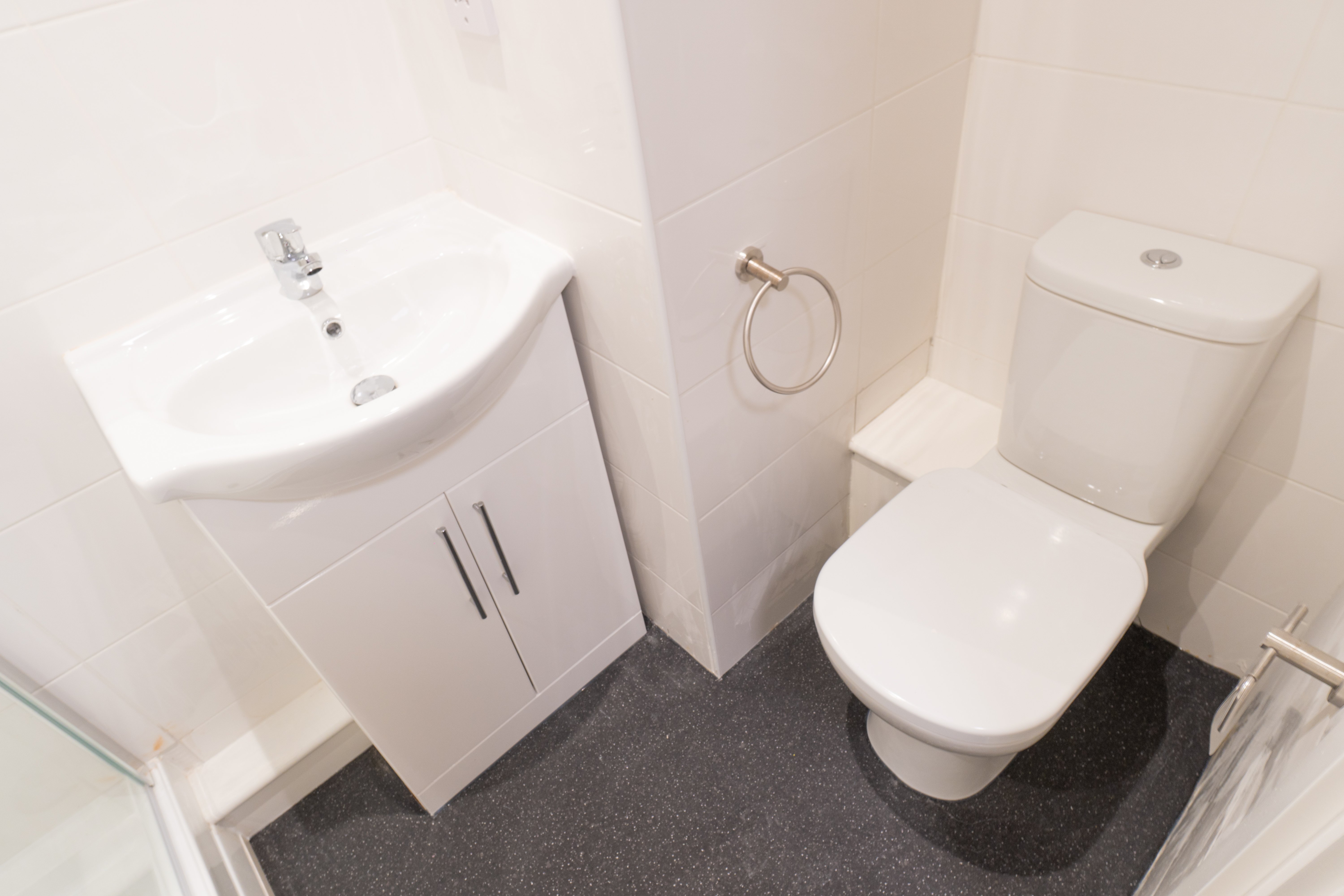 top view of a small bathroom with white sink and toilet. the floors are in grey tiles